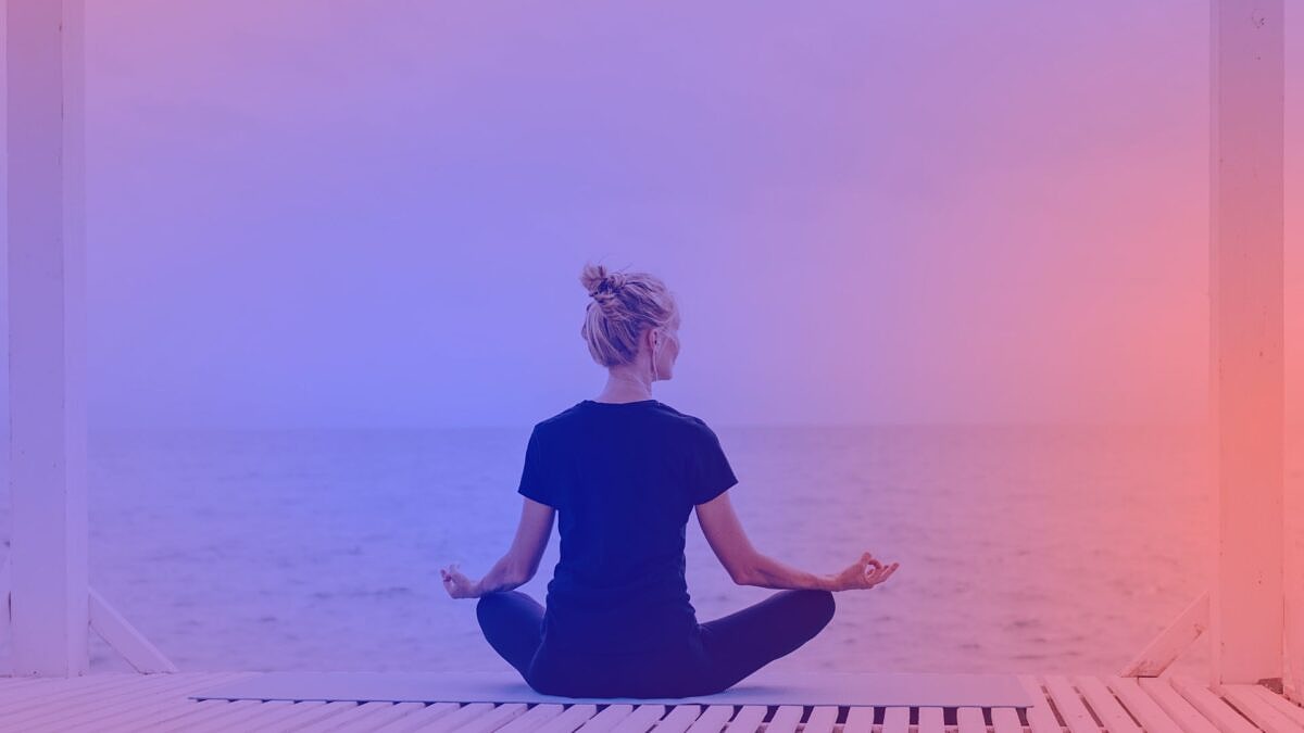 Mental Health Marketing: Eine Frau sitzt am Strand und meditiert.
