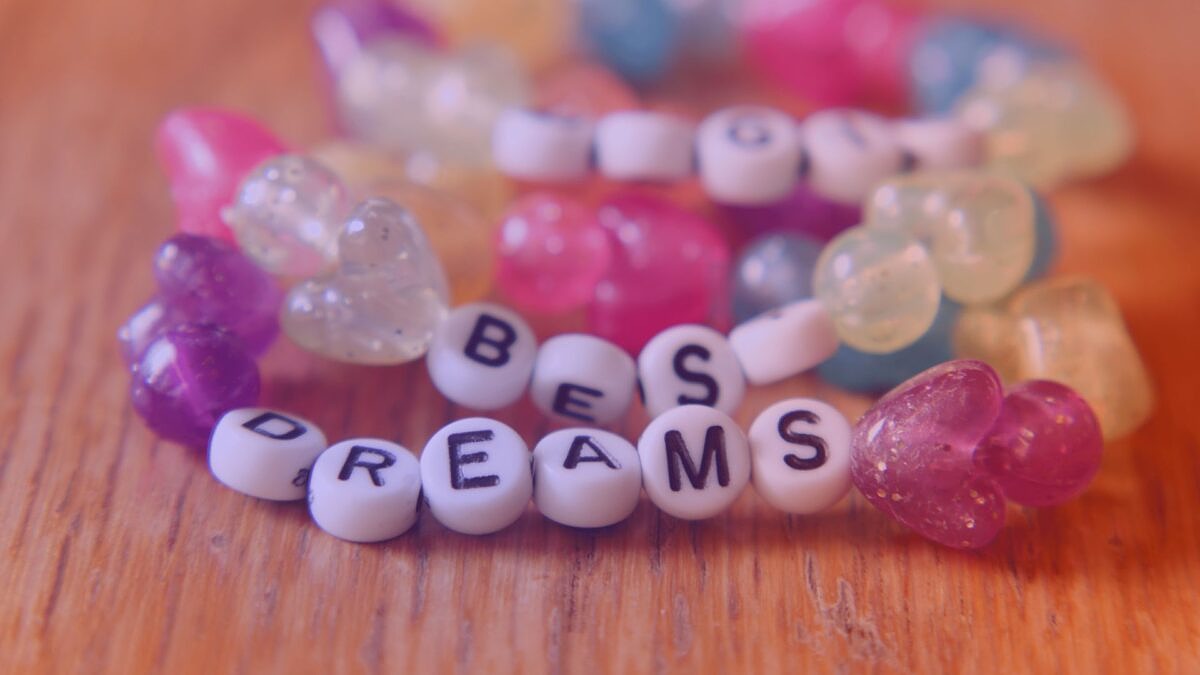 Close-up of colorful beaded bracelets with hearts and letters showing the words 'Best Dreams' - creative representation in the context of Taylor Swift's marketing.