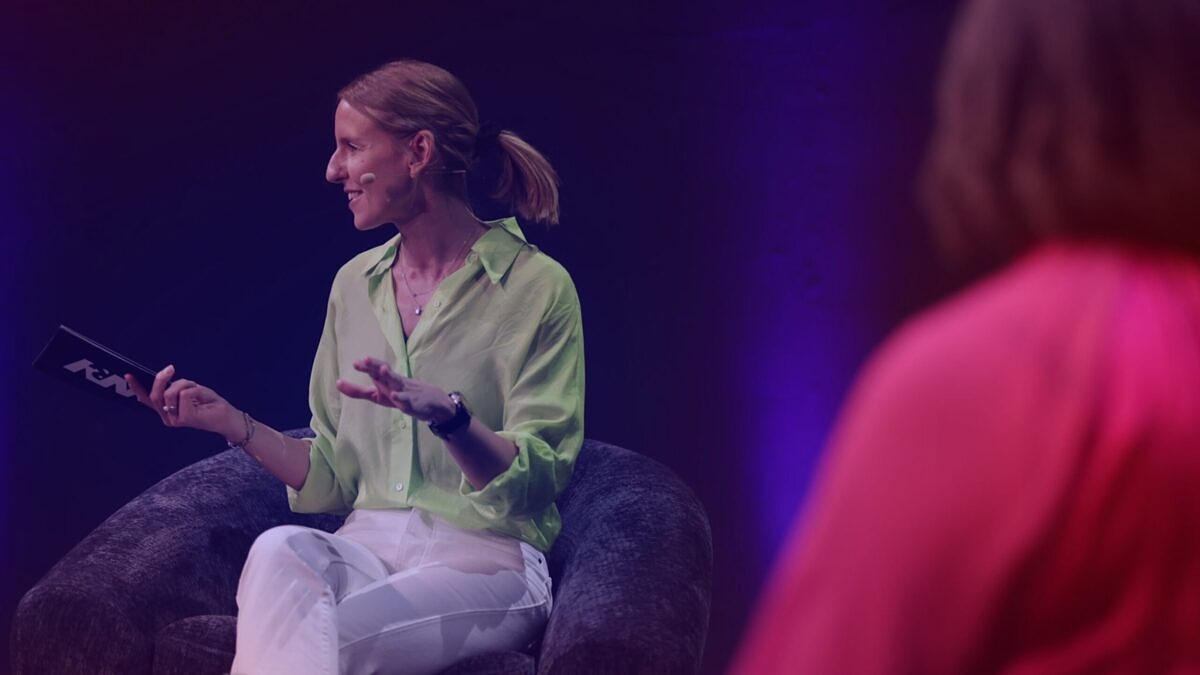 Brand Relevance: DMEXCO host Verena Gründel, wearing a bright green shirt, speaks on stage during a panel discussion.