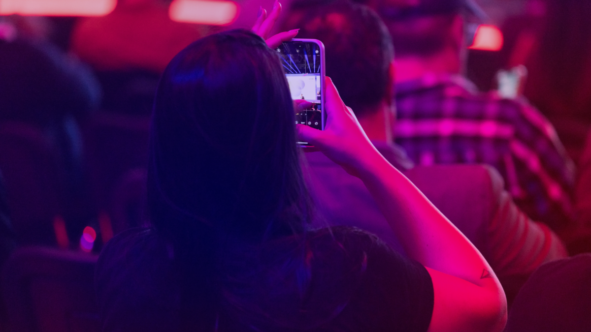 Besucherin fotografiert die Bühne mit dem Smartphone in der World of Media auf der DMEXCO 2025