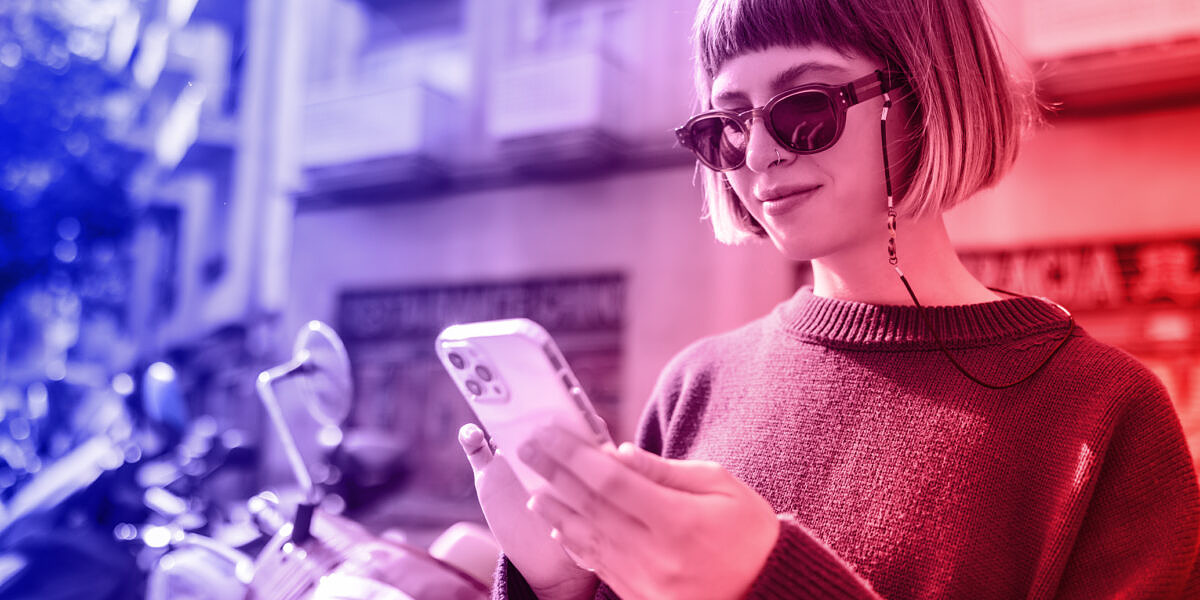 Revolutionize your marketing on TikTok: A young woman standing on her balcony with her cell phone.