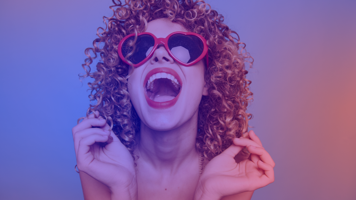 Top 10 reasons why DMEXCO is the must-attend marketing networking event of the year – symbolized by a jubilant woman with curly hair wearing red heart-shaped sunglasses.